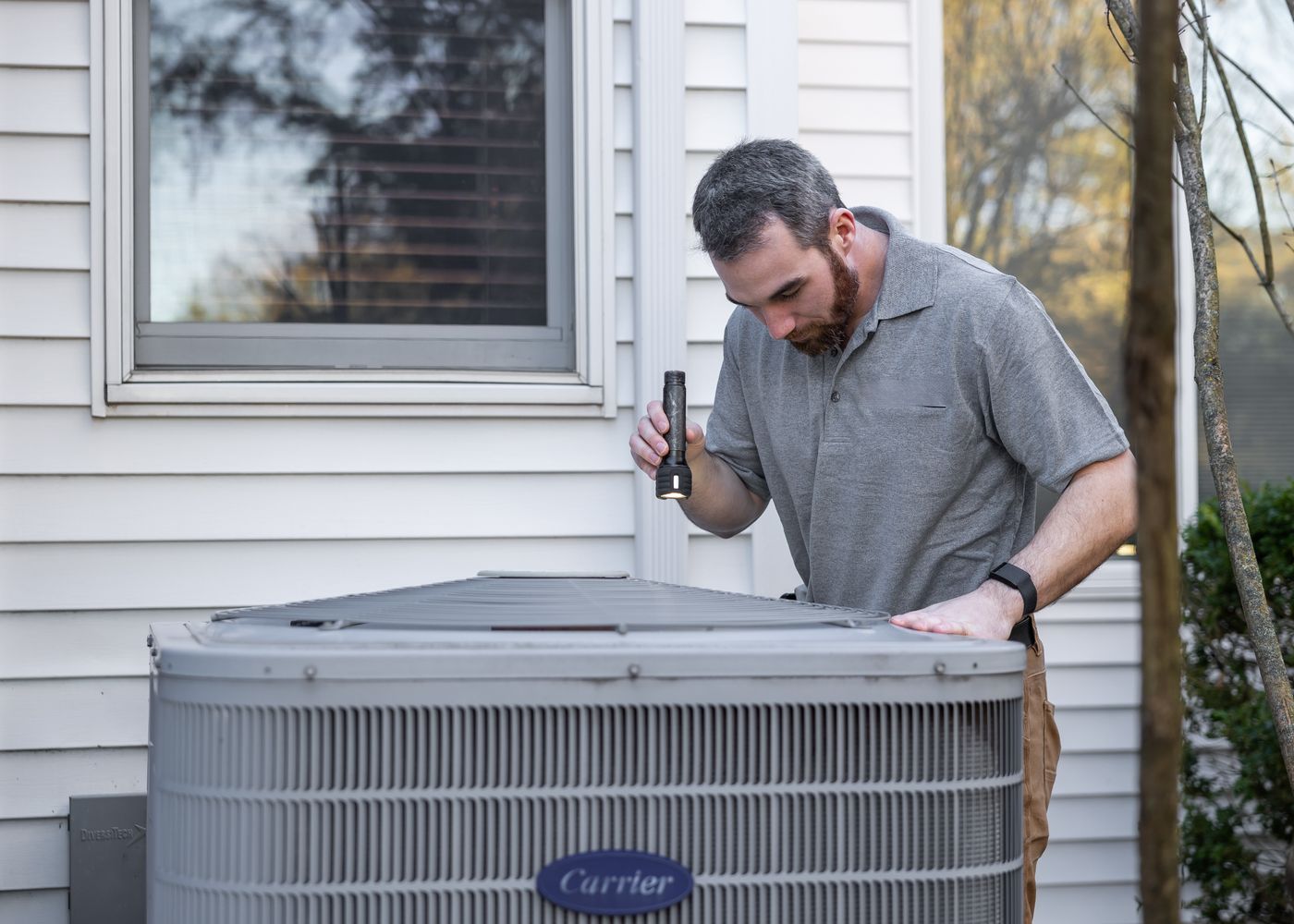 HVAC technician inspecting an outdoor air conditioning unit